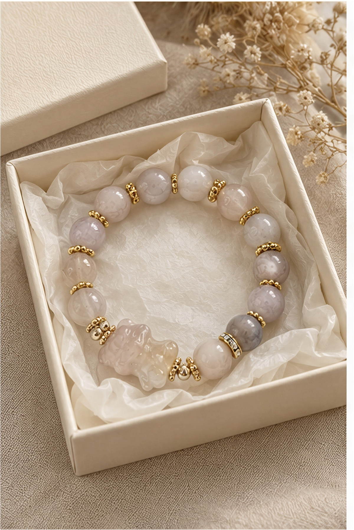 Sakura Agate carved bear bracelet worn on a wrist beside a cream knit sleeve.