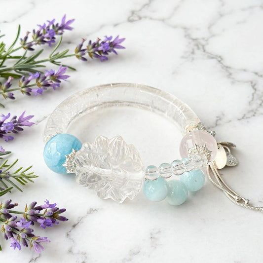 Clear quartz and aquamarine bangle bracelet with a carved clear quartz focal detail, transparent bead accents, and pale blue stones.
