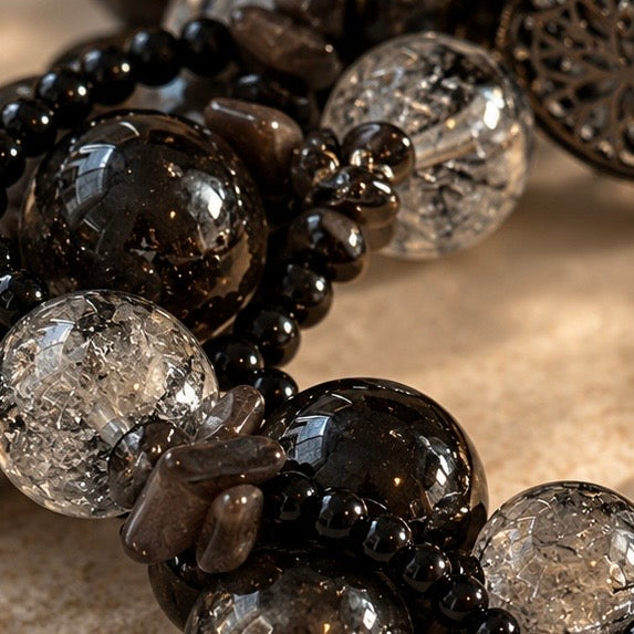 Close-up of glossy dark round beads, clear beads with internal texture, smoky-toned chips, and petite black bead rows.