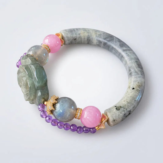 Labradorite bangle bracelet worn on a wrist, showing its curved silhouette and colorful bead accents.