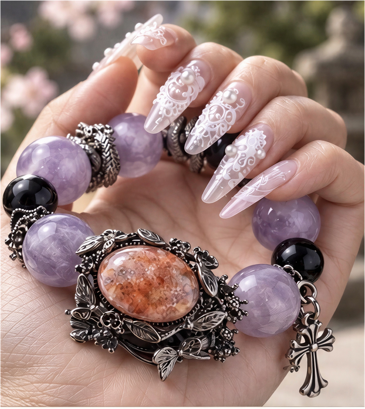 Amethyst bracelet held in a palm with oval Fire Quartz focal stone, botanical silver-tone setting and cross charm.