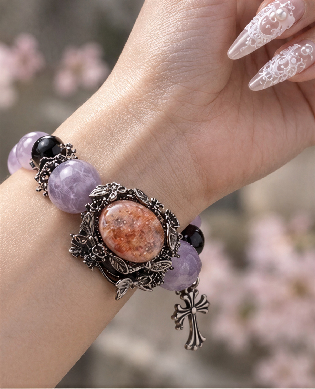 Close-up of oval peach-toned Fire Quartz framed by silver-tone flowers, leaves and butterflies.