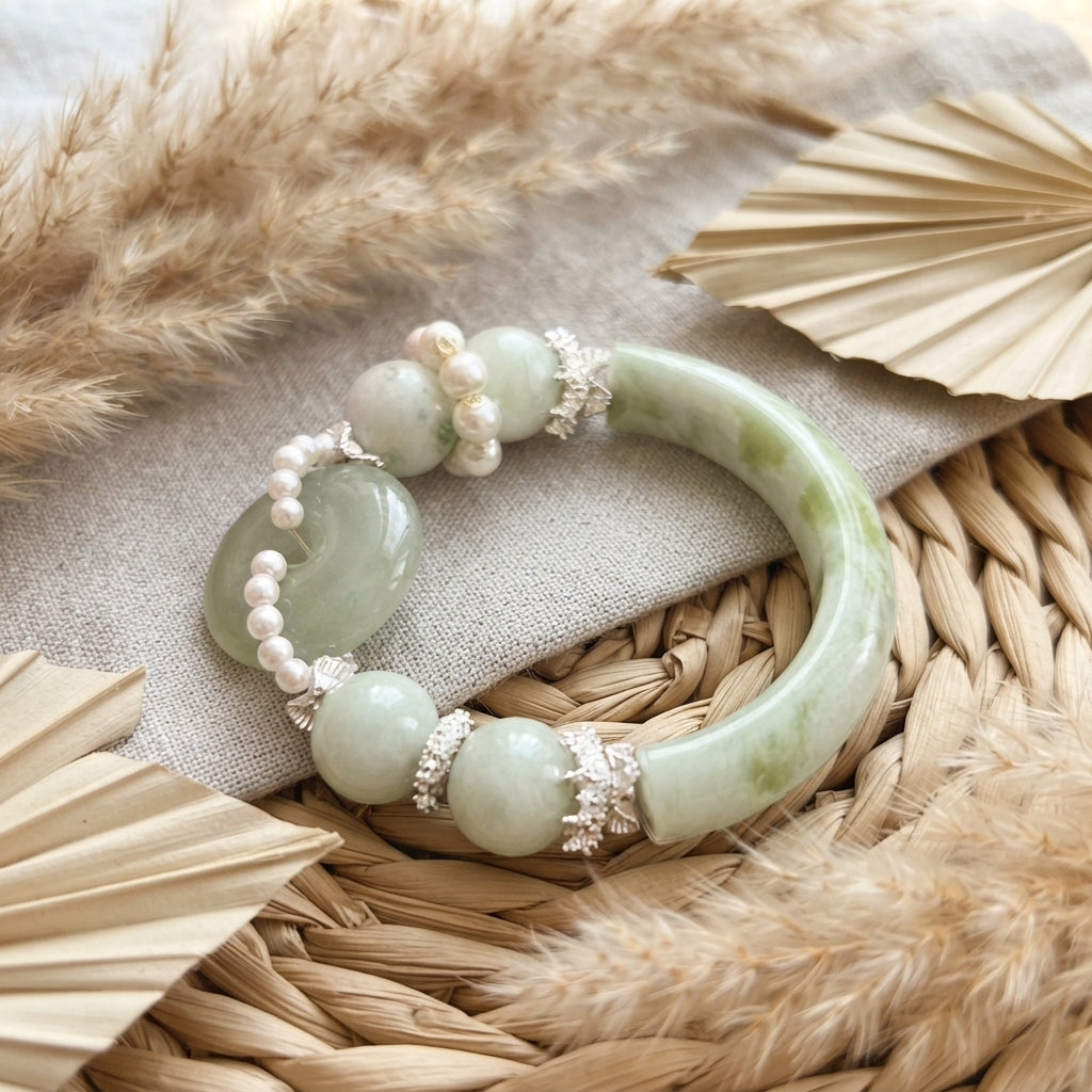 Nephrite jade bangle and pearl bead strand close-up on linen and rattan