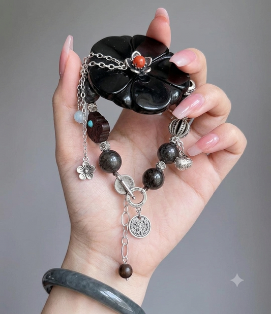 Close-up of black obsidian flower pendant with red coral center and silver chain detail