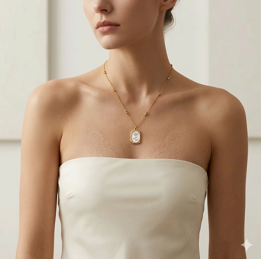 Woman wearing a gold necklace with a pendant on a neutral background