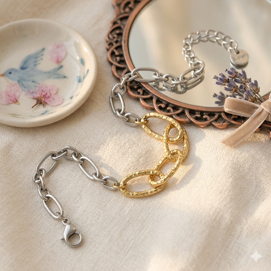 Two bracelets, one gold and one silver, on a textured surface with decorative elements.
