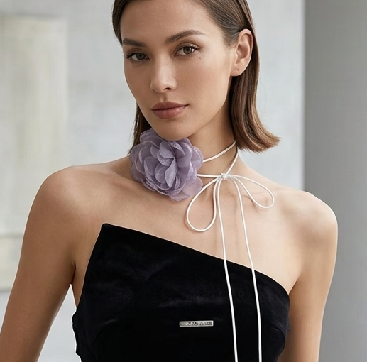 Woman wearing a black one-shoulder dress with white accents in a minimalistic room.