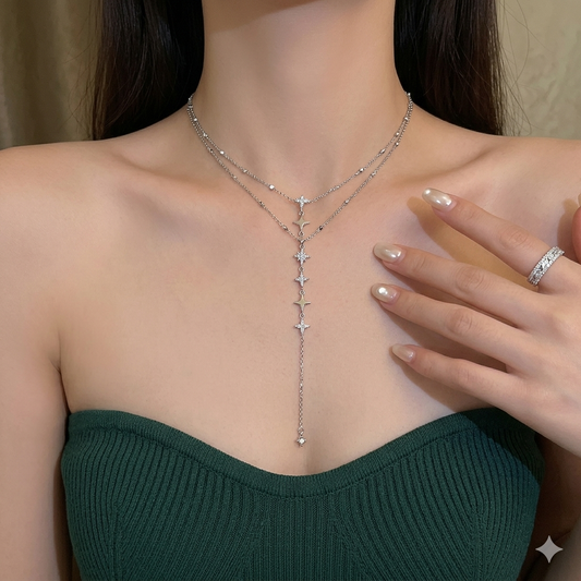 Woman wearing a silver necklace with crosses, green top, and ring on beige background