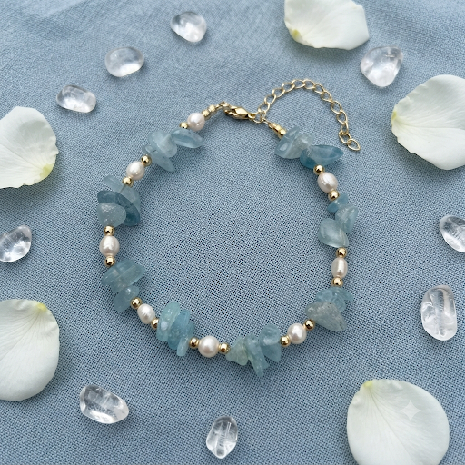 Aquamarine chip and freshwater pearl bracelet flat lay on cream linen