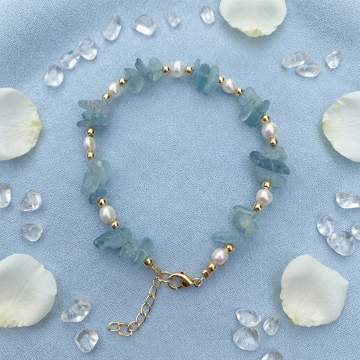 Aquamarine chip and freshwater pearl bracelet on blue linen with white petals