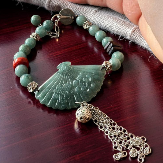 Blue water jade fan pendant bracelet with silver tassel held in hand