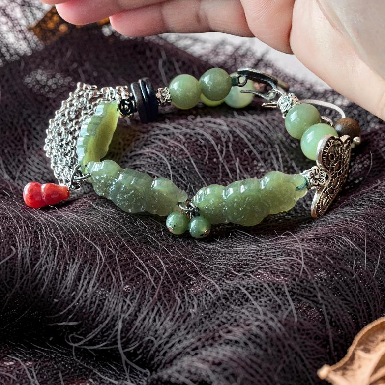 Green jade hand carved sakura flower bracelet with carnelian hulu charm on dark mesh fabric