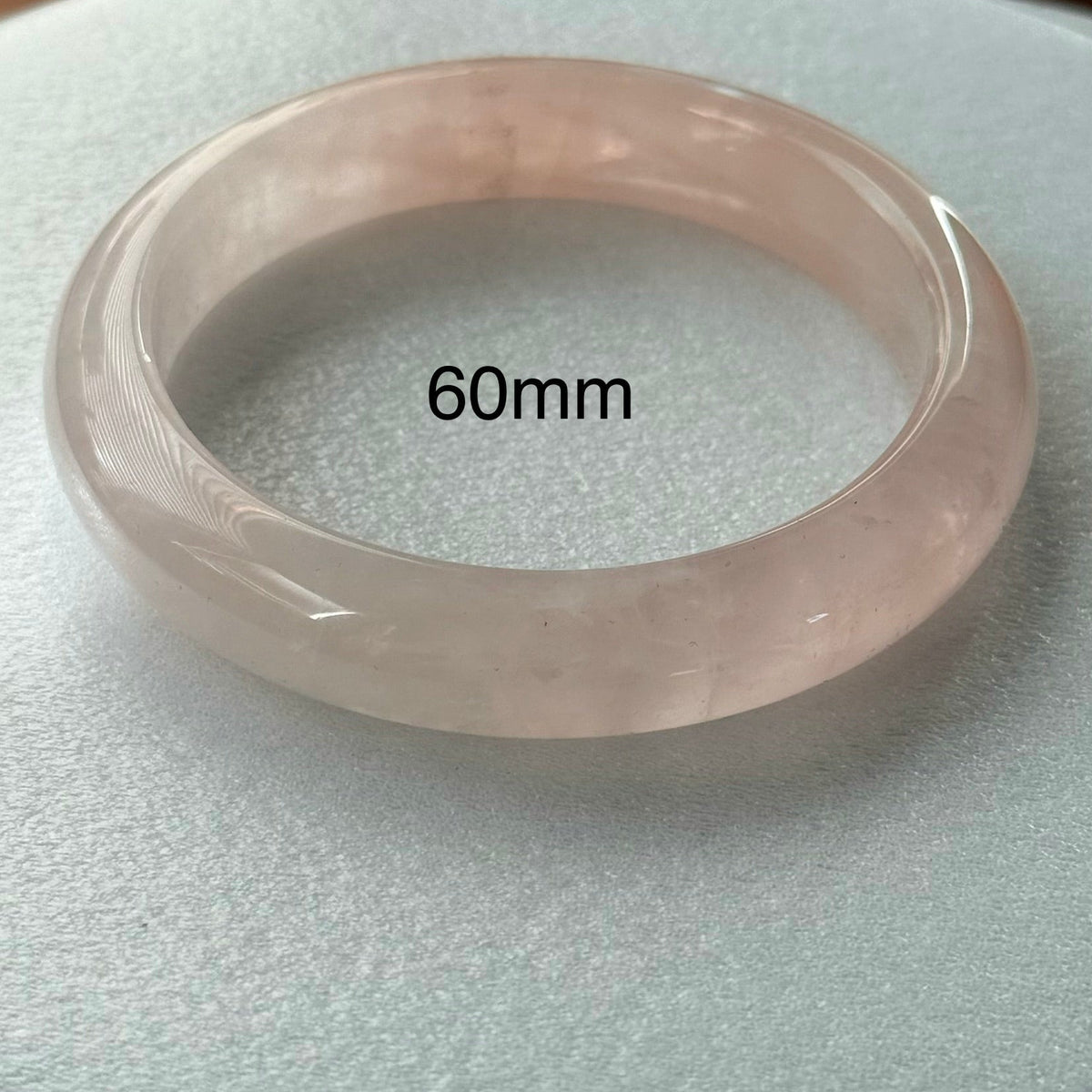 A translucent pale pink bangle bracelet displayed on a light gray textured surface, with a black text overlay reading '60mm'.