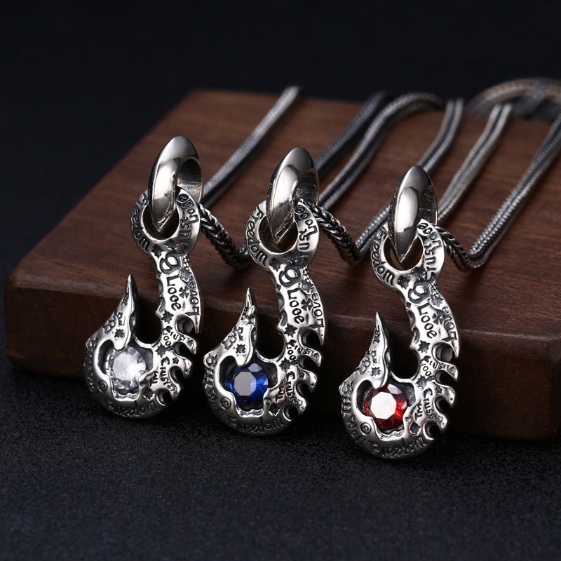 Three silver pendants with gemstones on a wooden surface
