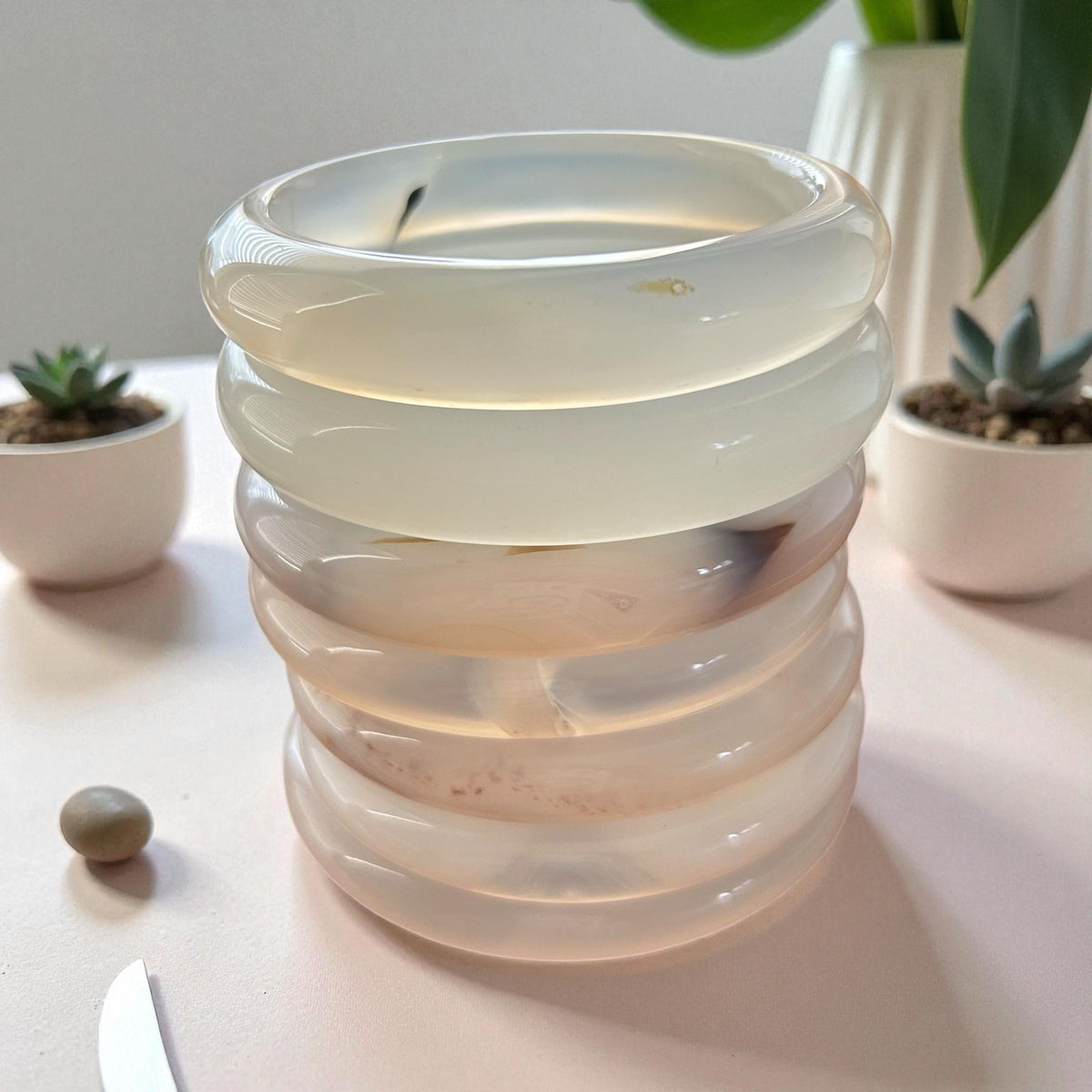 Stacked glass candle holder on a table with plants in the background